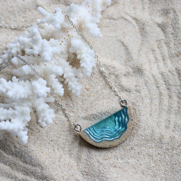 Dainty beach sand and blue resin necklace close up with sand background