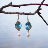 Bay small beach sand and pearl dangle earrings on branch with water in background