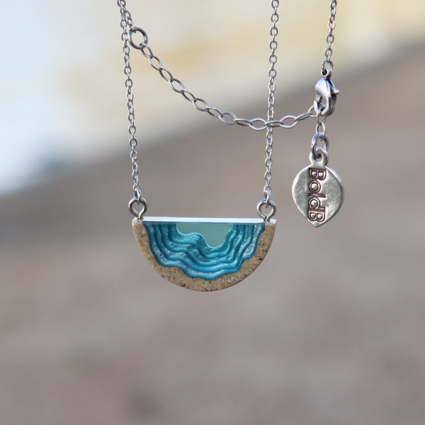 Dainty beach sand and blue resin necklace with beach background